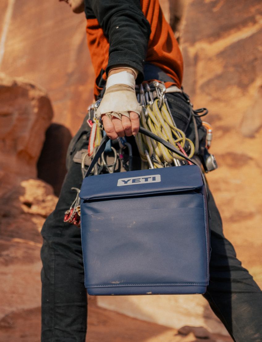 Person holding a blue YETI  Daytrip cooler in a desert setting