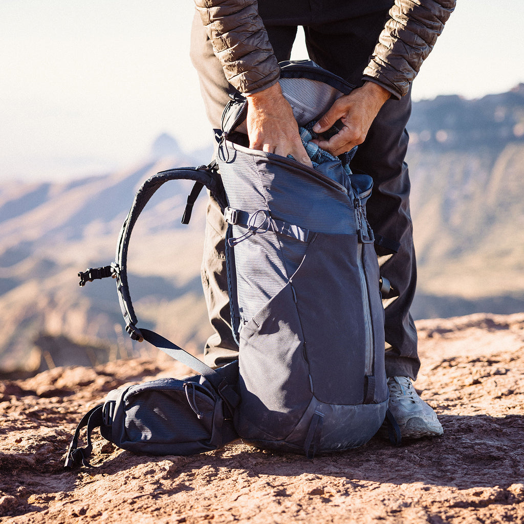 Person adjusting a backpack on a mountainous landscape