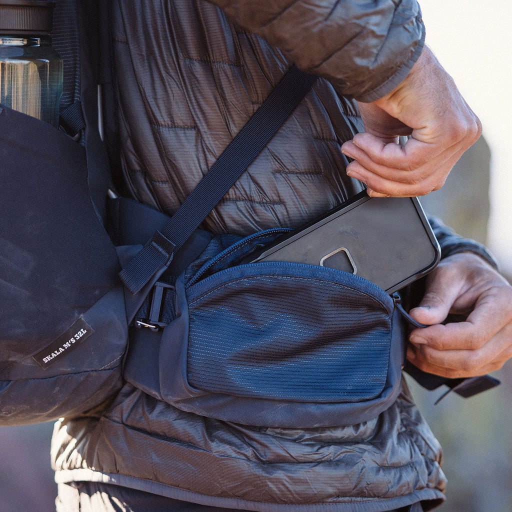Person wearing a backpack with a phone in hand, blurred background