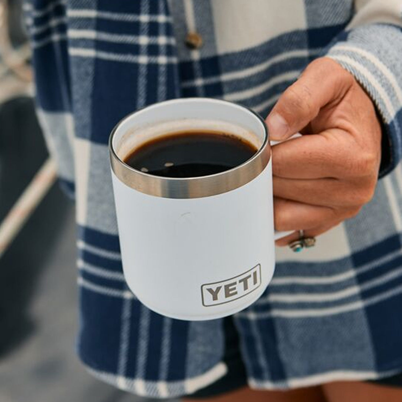 Person holding a YETI branded mug with coffee