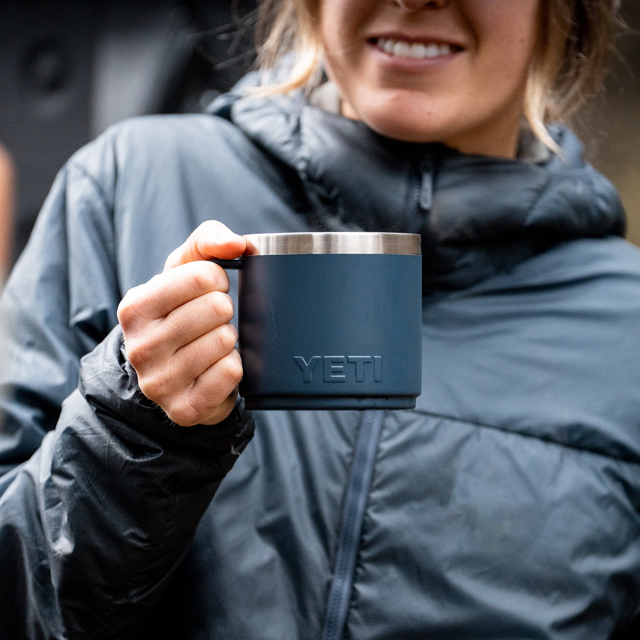 Person holding a YETI mug outdoors