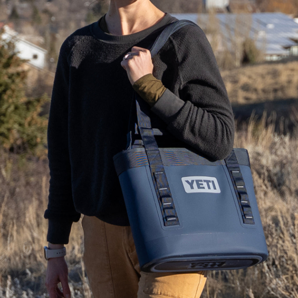 Person holding a YETI Camino bag outdoors with a scenic background