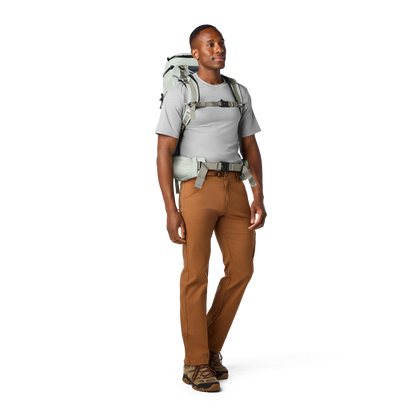Person wearing a hiking backpack and brown trousers on a white background