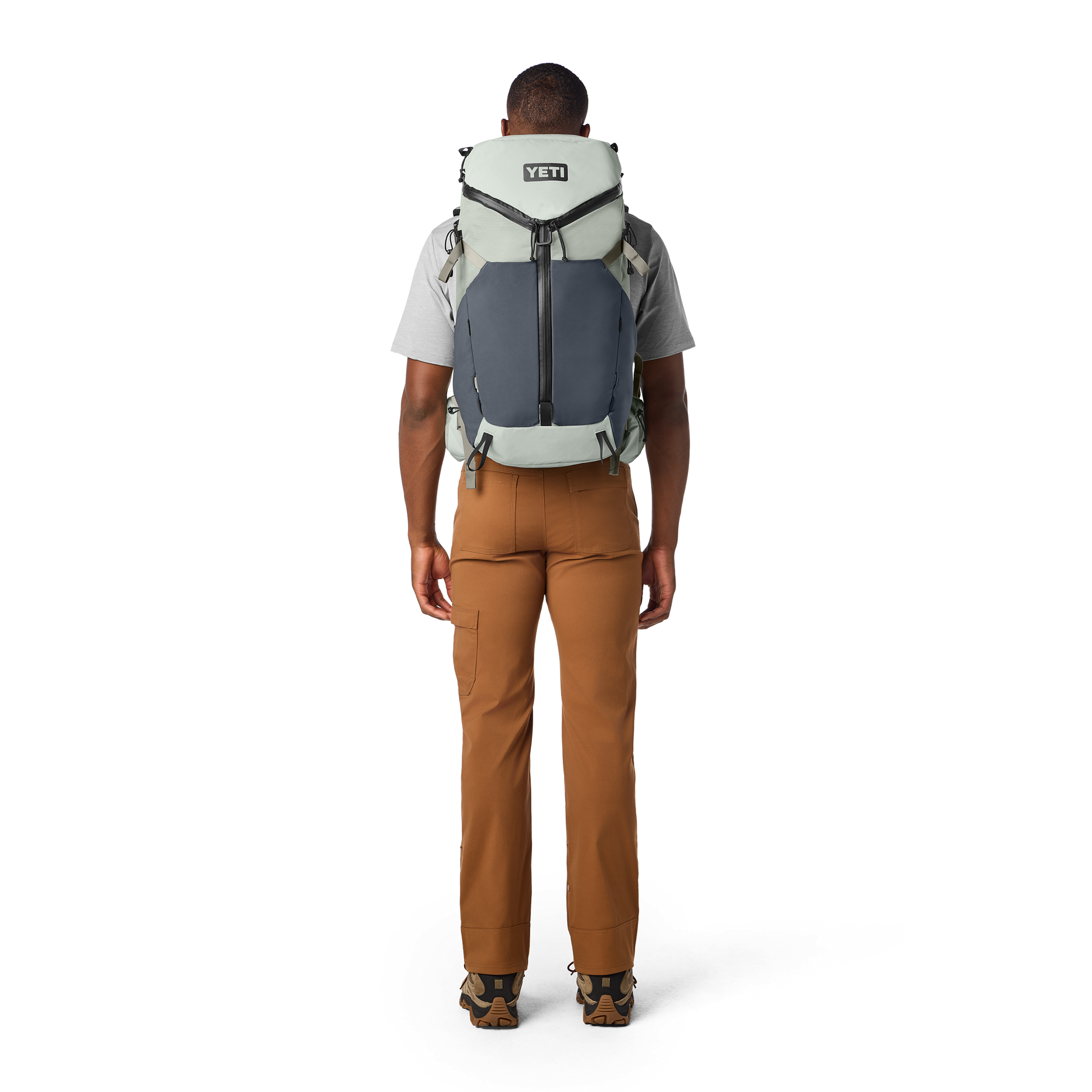 Person wearing a YETI backpack on a white background