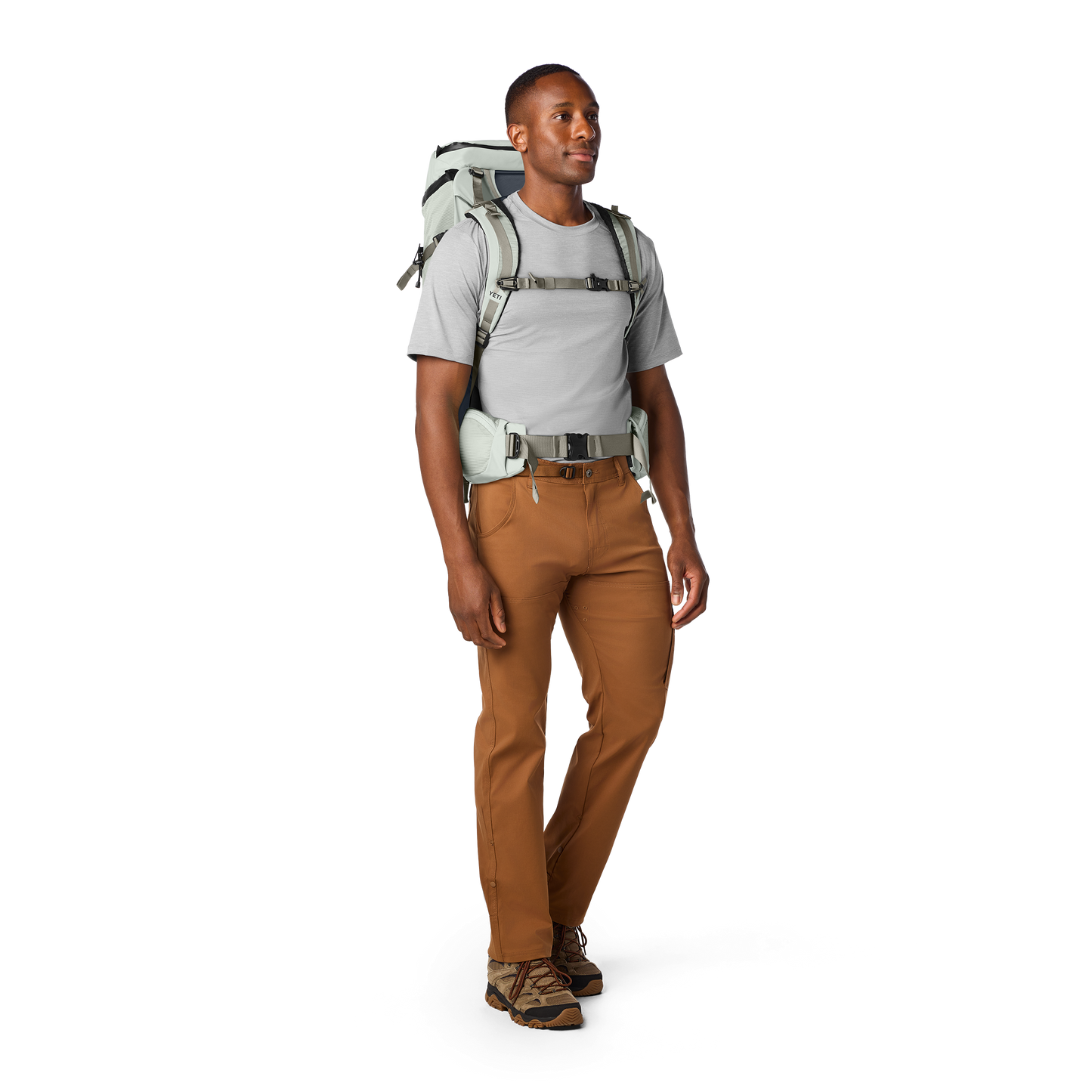 Man wearing a hiking backpack and brown trousers on a white background